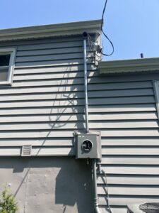 Exterior view of a residential electrical meter and service mast installation by In the Light Electrical LLC in Kansas City, KS