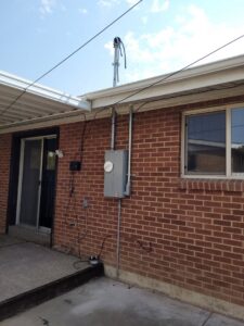 A residential electrical meter and service panel installed on the exterior of a brick house by All Aboard Services in Farr West, UT.