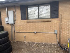 Exterior residential electrical meter and panel installation with conduit on a brick wall by P&E Electric in Denver, CO.