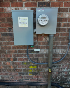 A residential electrical meter and service panel on a brick wall by Joule Electrical A/C & Heating Services in New Orleans, LA.