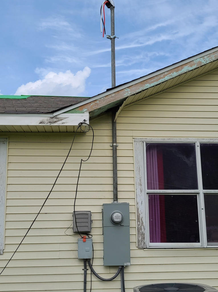 A residential electrical meter and service mast installed on the side of a house by ECS. Electrical Contracting Services LLC in Lake Charles, LA.