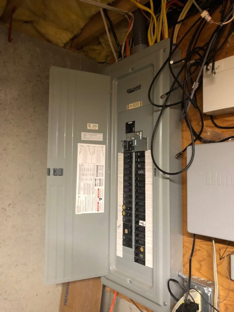 An open residential electrical panel with circuit breakers and wiring, indicating electrical service by Peeler Electric Light & Power in Merrimack, NH.