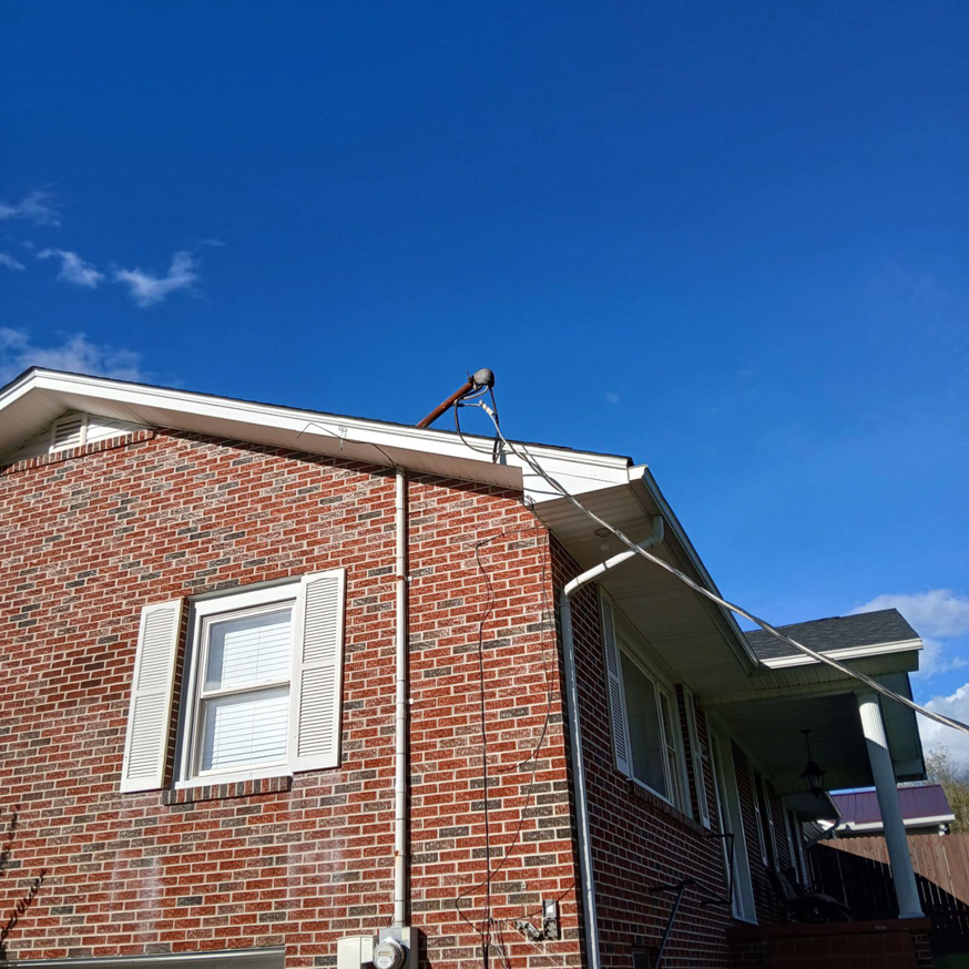 Residential electrical service mast and wiring on the roofline of a brick house by KW Electric in Johnson City, TN