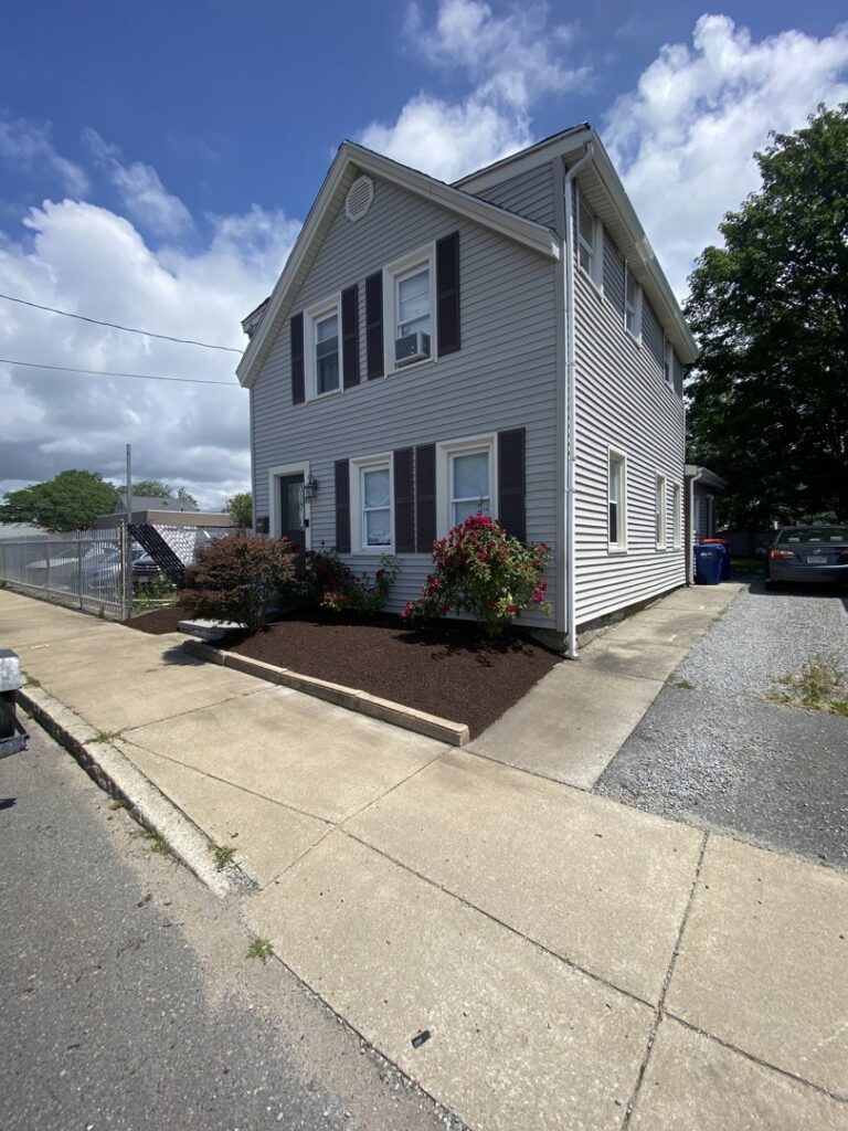 A residential flower bed with fresh mulch and blooming roses by Chaves Lawn Care in New Bedford, MA
