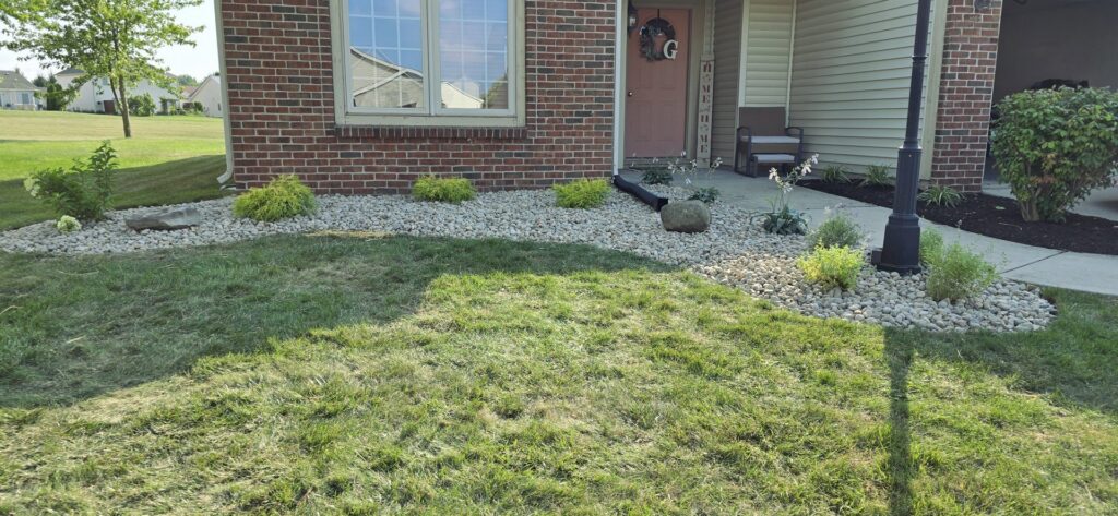A residential front yard featuring a combination of mowed grass and decorative rock landscaping by Three Rivers Lawn Care Co. in Fort Wayne, IN.