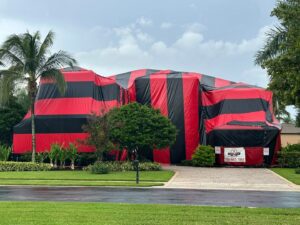 A large residential house covered in a red and black fumigation tent by PNP Pest Solutions LLC in Miami, FL.