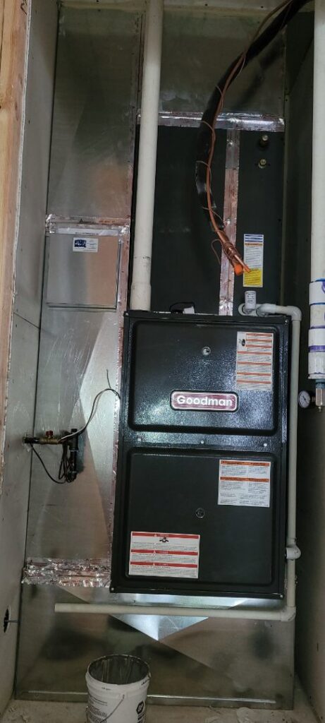 A Goodman residential furnace and air handler unit with ductwork installed in a framed closet by Integrity Heating And Air LLC in Nampa, ID