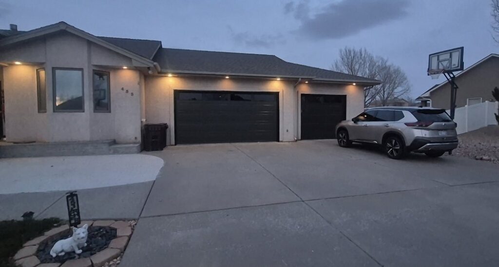 A residential house featuring two newly installed dark grey garage doors by Prutch's Garage Door in Colorado Springs, CO.