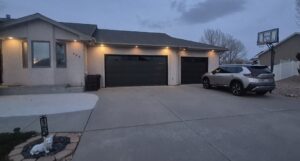 A residential house featuring two newly installed dark grey garage doors by Prutch's Garage Door in Colorado Springs, CO.