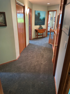A long residential hallway featuring newly installed dark grey carpet by Johnson Flooring in Newberg, OR.