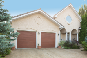 A residential home featuring two modern brown garage doors installed by Overhead Door Company of Central Missouri in Columbia, MO.