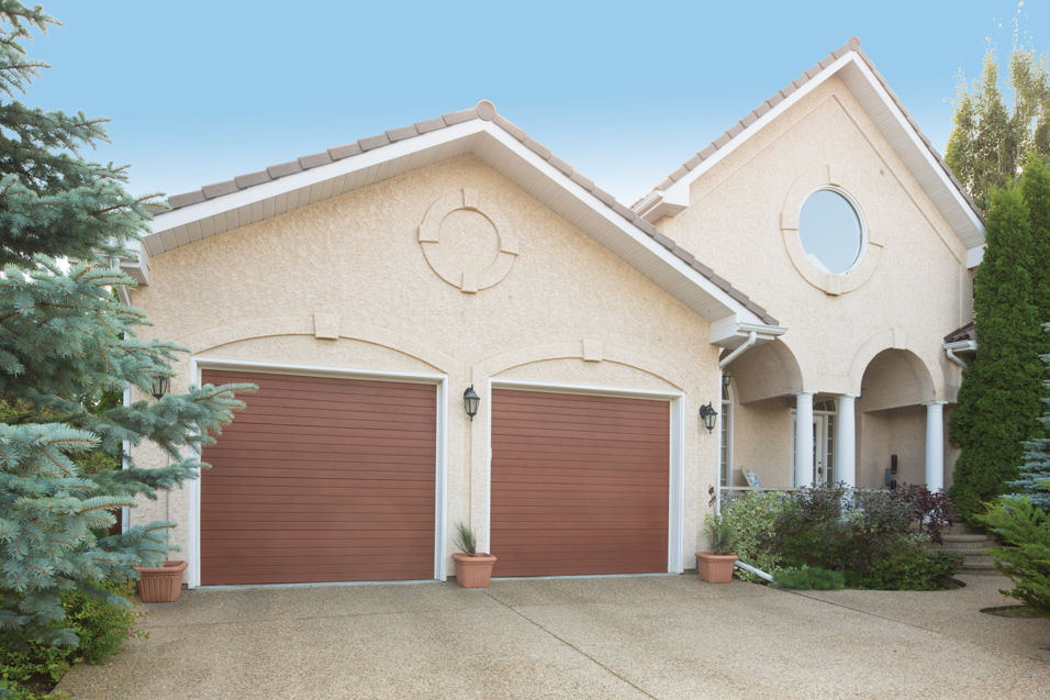 A residential home featuring two modern brown garage doors installed by Overhead Door Company of Central Missouri in Columbia, MO.