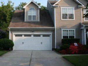 A residential house featuring a single white garage door, a service provided by Precision Garage Door of Charleston in North Charleston, SC.