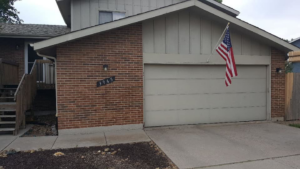 A residential house showcasing a well-maintained beige garage door by Million Garage Door Services in Colorado Springs, CO.