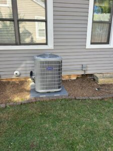 A new residential Carrier HVAC condenser unit installed outside a house with gray siding by Legacy Hvac/r in Libertyville, IL.