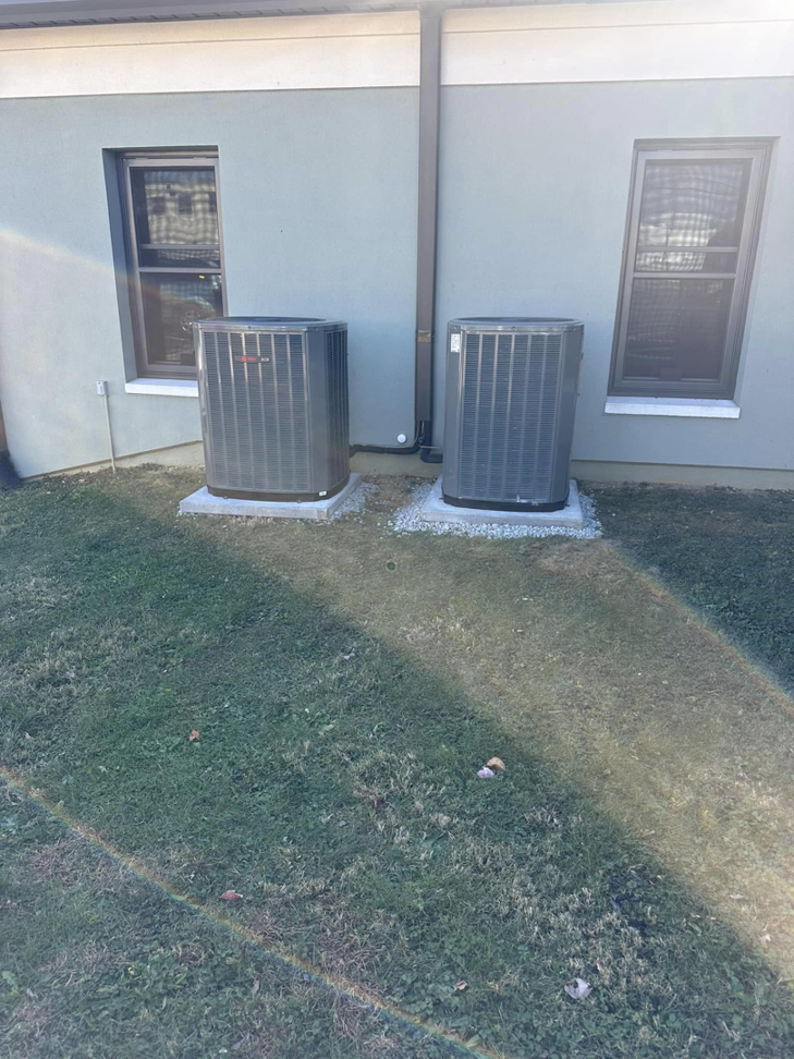 Two outdoor HVAC condenser units installed on concrete pads next to a residential building by R&R Climate Systems in Newark, NJ