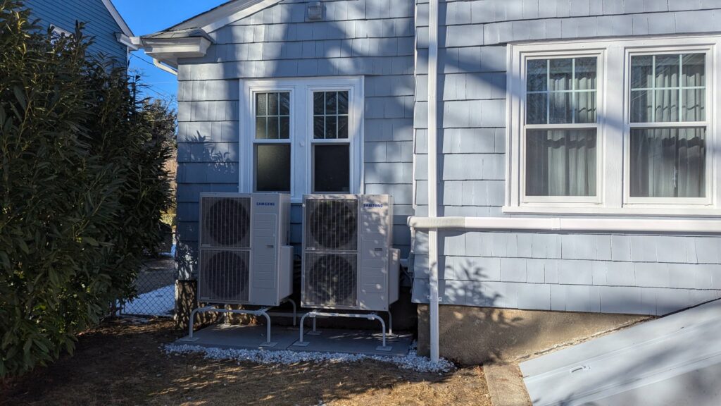 Two Samsung outdoor HVAC units installed on the side of a residential home by WARM Global HVAC in East Providence, RI.