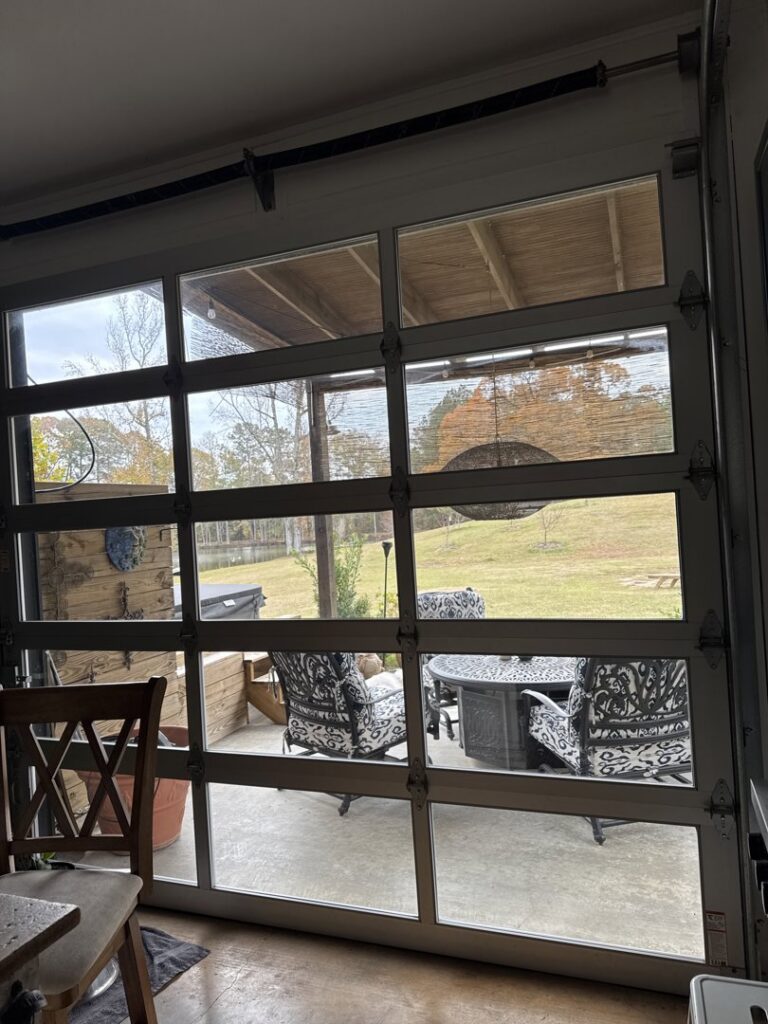 An interior view of a residential full-view glass garage door opening to a patio, installed by Monroe Overhead Doors in Monroe, LA.
