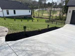 Residential landscaping with fresh mulch along a driveway by All Things Lawncare in Knoxville, TN.