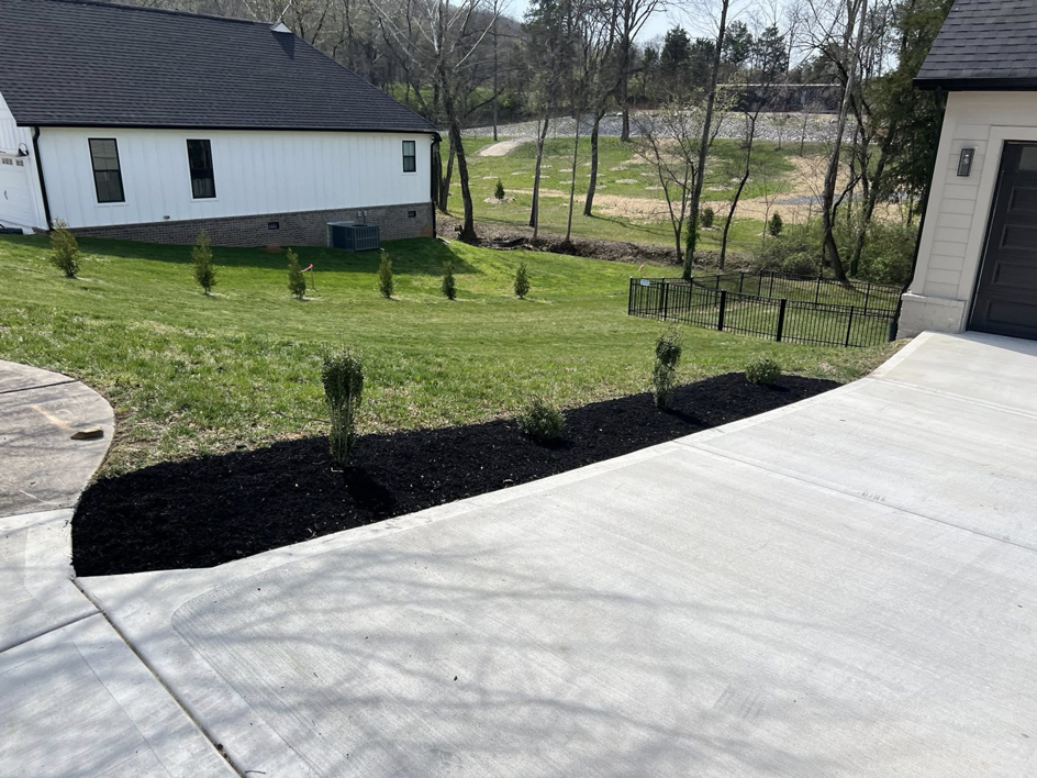 Residential landscaping with fresh mulch along a driveway by All Things Lawncare in Knoxville, TN.