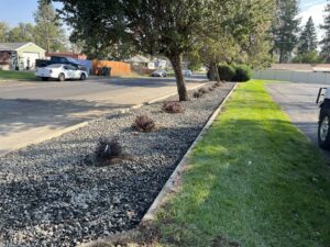 A residential property featuring a neatly mowed lawn alongside a decorative gravel bed with small plants, maintained by McLain Lawn & Landscape in Spokane, WA.