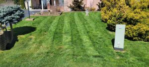 A well-maintained residential lawn with distinct mowing stripes in front of a house, provided by Parks' Lawn Care in Hagerstown, MD.