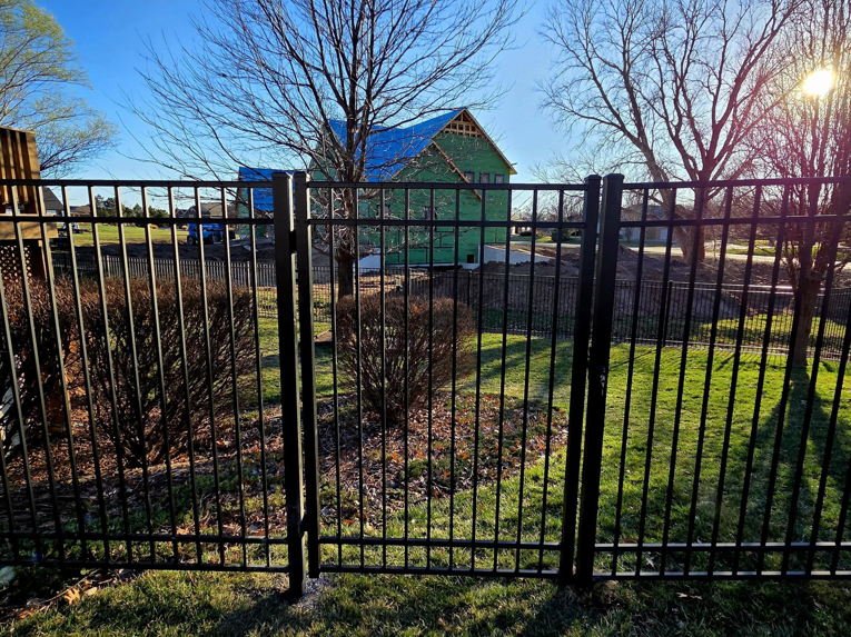 A black metal fence with a gate installed in a residential area by Green Acres Fence Co in Salina, KS.