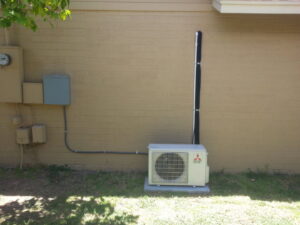 A residential mini-split HVAC condenser unit installed next to a building, serviced by Kade Mechanical in Phoenix, AZ.