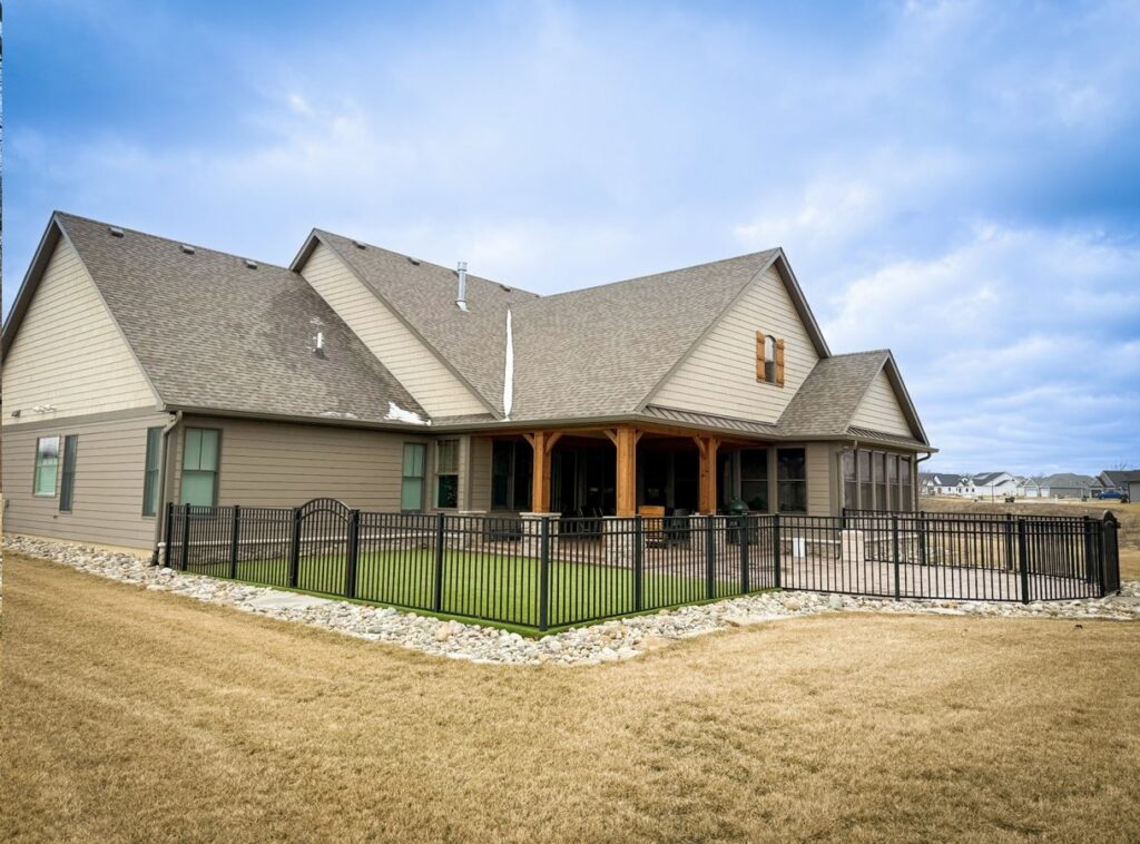 A residential property featuring a black ornamental fence enclosing a patio area by Sharper Image Fence in Fort Wayne, IN.