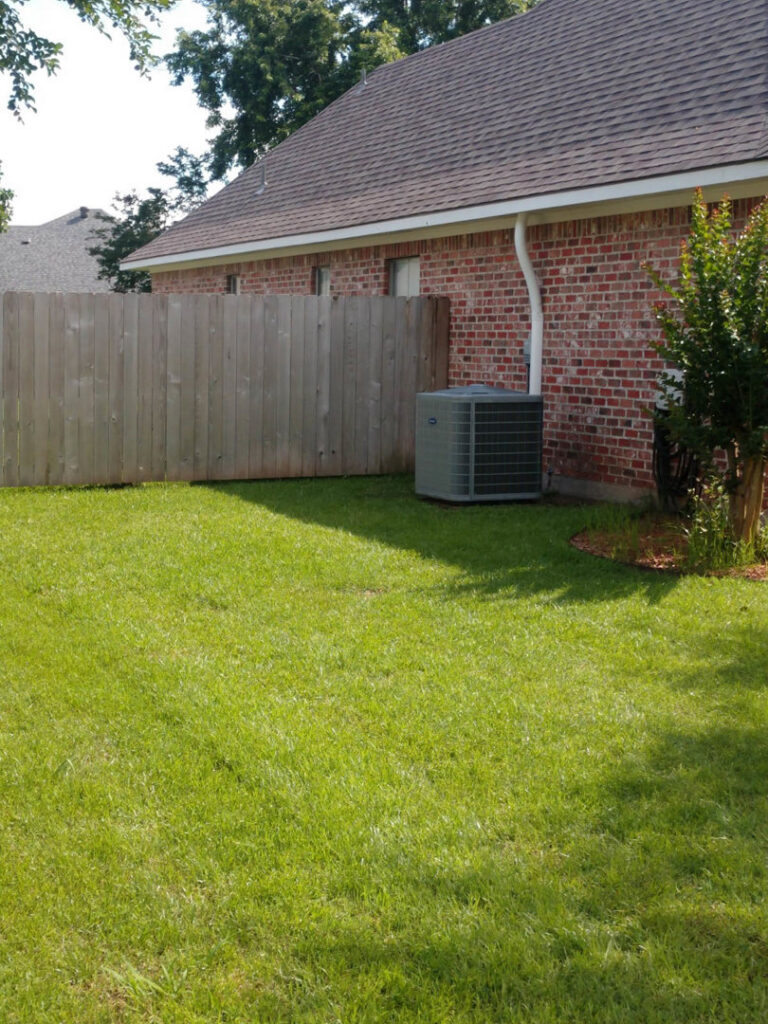 A residential outdoor air conditioning unit installed next to a brick house, serviced by ARKLA AIR LLC in Springhill, LA.