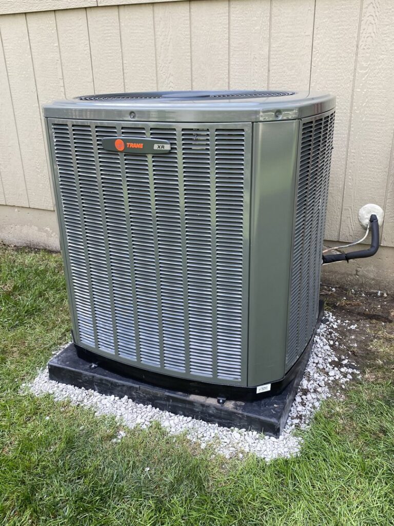 A residential outdoor air conditioning unit installed on a gravel pad by Pro-Cool Air Conditioning & Heating in Blue Springs, MO.