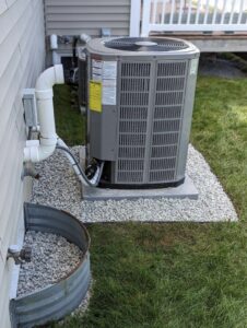 A residential outdoor air conditioner unit installed on a gravel bed by PureTemp Heating and Cooling in Salem, NH.