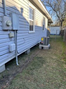 A residential outdoor HVAC condenser unit installed outside a home by Budget Heating and Air in Mobile, AL.