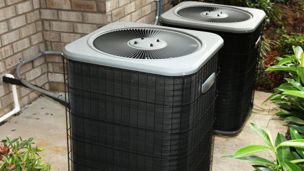Two residential outdoor HVAC condenser units installed next to a brick home by Tim Force Tin Shop in Casper, WY.