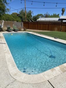 A residential swimming pool being cleaned by an automatic cleaner, provided by BEHR POOLS Service & Repairs in Glendale, AZ
