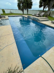 A beautifully clean residential swimming pool with a hose, indicating recent cleaning by Brocks Pools LLC in Baton Rouge, LA.