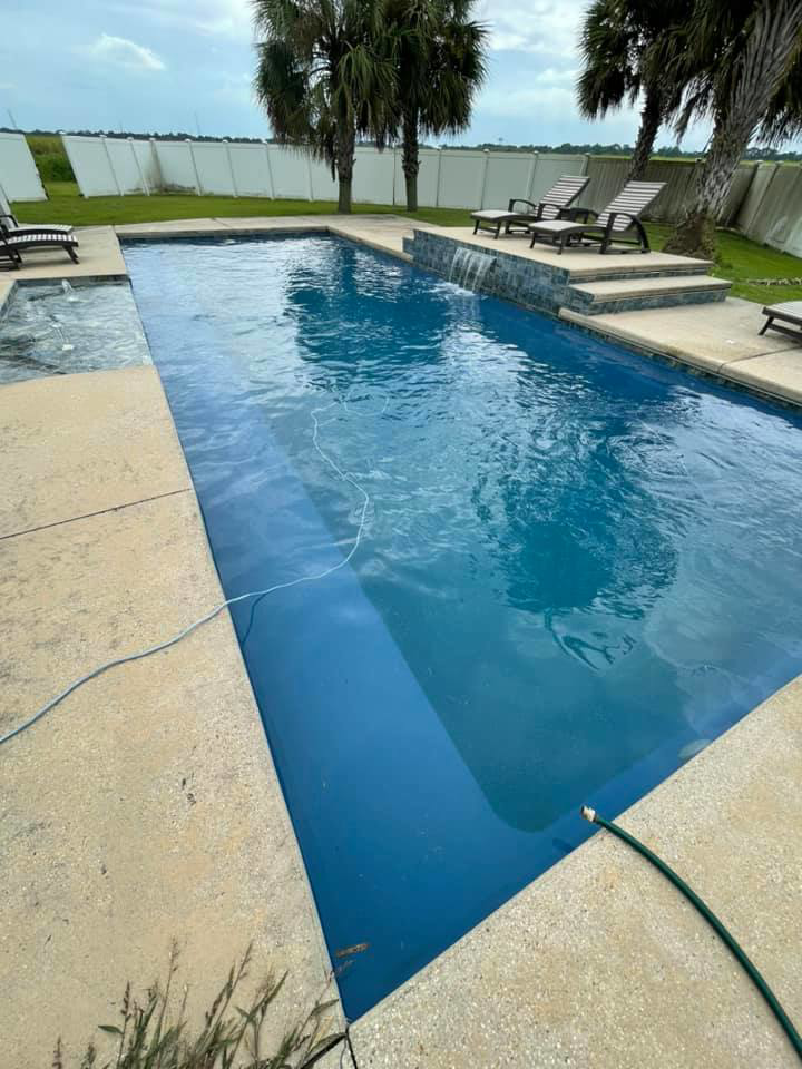 A beautifully clean residential swimming pool with a hose, indicating recent cleaning by Brocks Pools LLC in Baton Rouge, LA.
