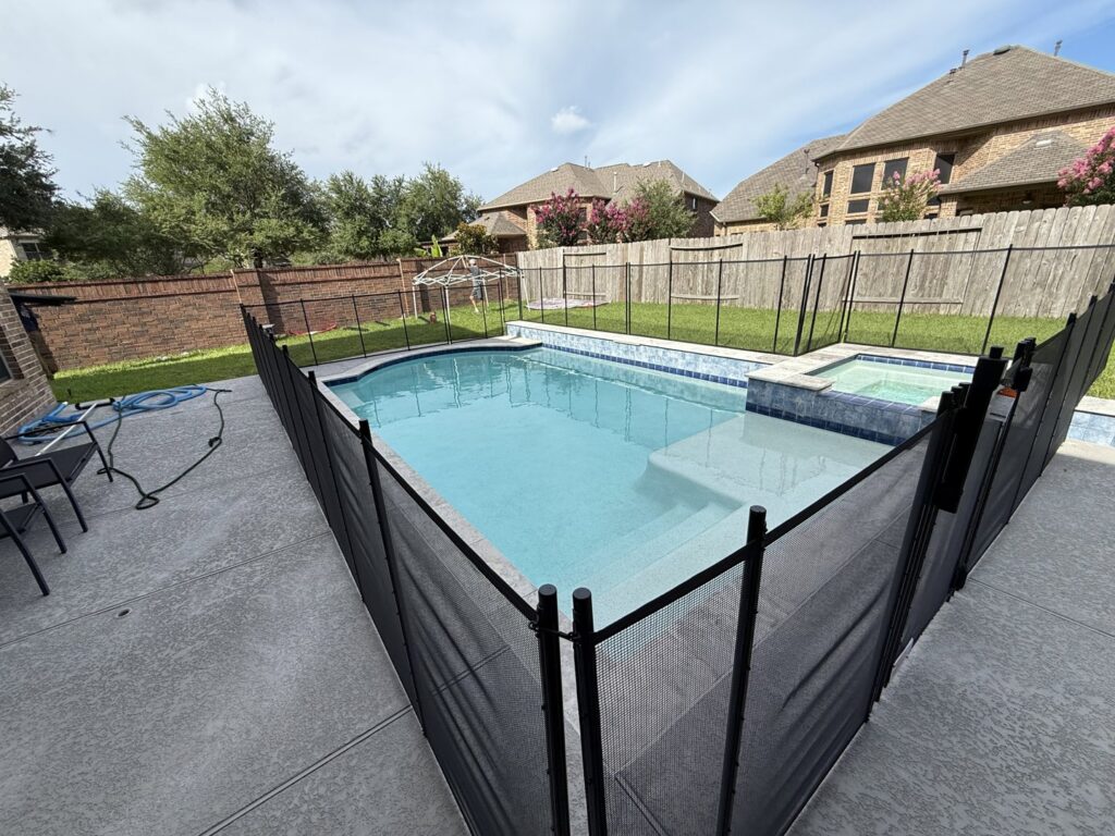 A completed residential pool fence project featuring a black mesh barrier by Lone Star Pool Fence in Houston, TX.