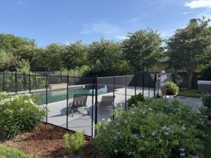 A residential pool fence solution featuring a black mesh barrier by Lone Star Pool Fence in Houston, TX.