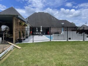 A black metal fence installed around a residential swimming pool area by Southern Fencing, LLC in Houma, LA.