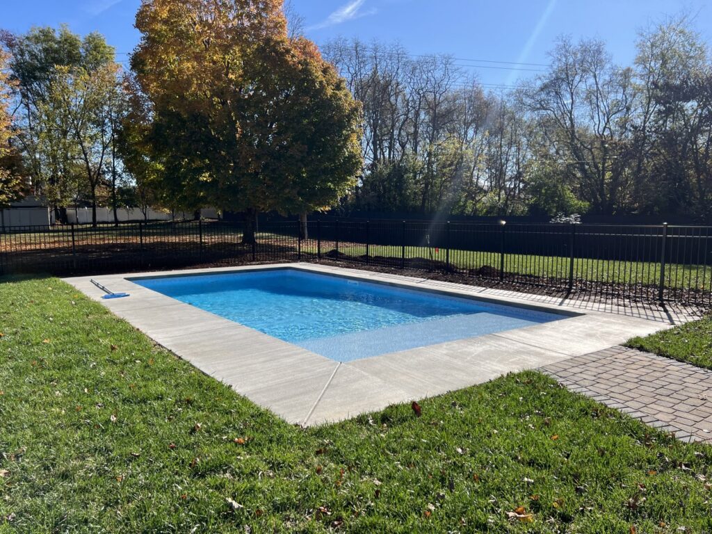 A residential inground pool with concrete surround in a well-maintained grassy yard, installed by Riverstone LLC in Bowling Green, KY.