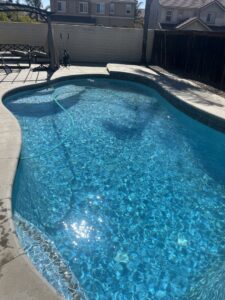 A residential swimming pool with a cleaning hose visible, showcasing pool maintenance by Good Guy Pool Service in Moreno Valley, CA.