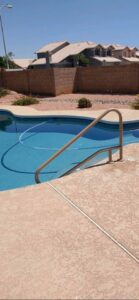 A residential pool with clear blue water and a cleaning hose, demonstrating routine pool service by Space Ranger Pools in Gilbert, AZ.