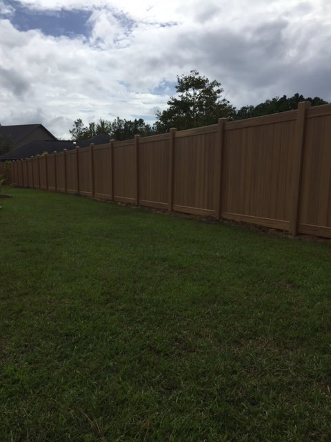 A long, sturdy residential privacy fence in a light brown finish, installed by Custom Fence Builders in Gulfport, MS.