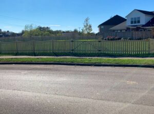 A long, attractive scalloped wooden privacy fence bordering a residential property, installed by Roark Fencing in Lexington, KY.