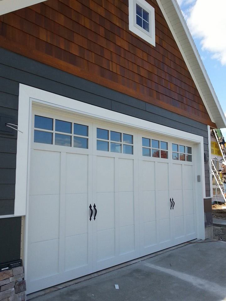 A white residential garage door with decorative hardware and windows, installed by Tri County Overhead Door Service Inc in New London, WI