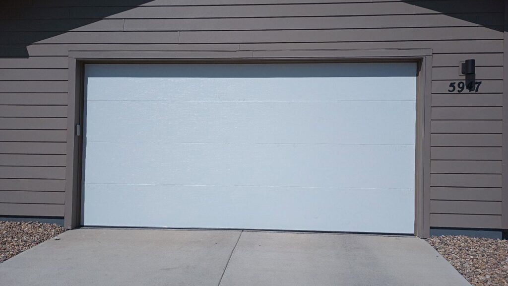 A newly installed white residential garage door by Front Range Raynor Garage Door & Service in Fort Collins, CO.