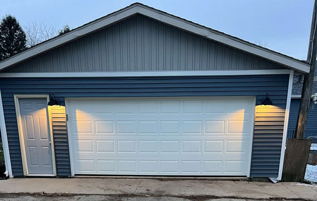 A newly installed white sectional garage door on a residential home by Tri County Overhead Door Service Inc in New London, WI