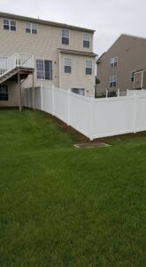 A newly installed residential white vinyl fence in a backyard by DZS Fencing, LLC in Red Lion, PA.