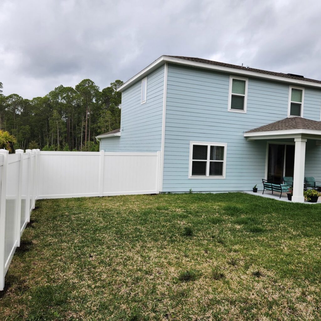 A residential property featuring a new white vinyl privacy fence, providing security and curb appeal from Exacta FENCE LLC in Jacksonville, FL.